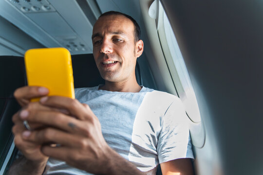 A man uses his smartphone during a flight in an airplane cabin