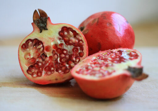 Freshly sliced open organic pomegranate with glossy, ruby-red arils bursting with juice, isolated with generous copy space for healthy food, wellness, and nutrition concepts.

