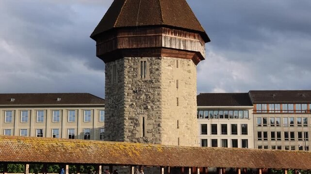 View of the historic Chapel Bridge and Wasserturm crossing the Reuss River with people walking along the wooden structure in Lucerne, Lucerne, Switzerland.