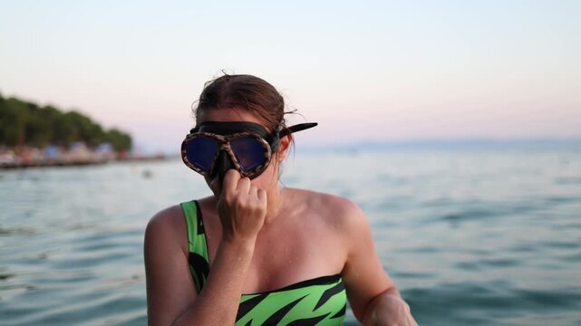 Young woman in snorkeling mask points to her ear before diving in the sea demonstrating pressure equalization and ear safety while exploring underwater on summer vacation