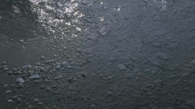 Ocean waves filmed at sunset as camera dives underwater and emerges showing split level views with bubbles and droplets