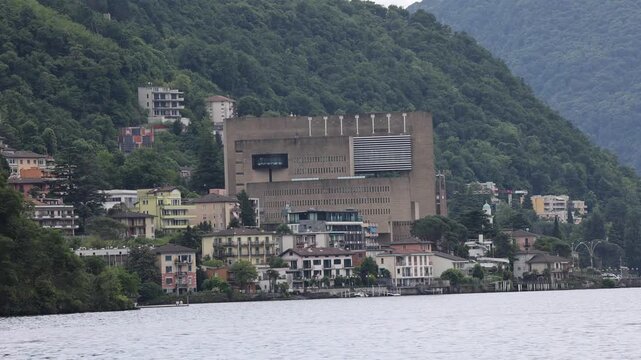 View of the iconic Casino di Campione building situated on the hillside overlooking the lake in Campione d'Italia, Lombardy, Italy.