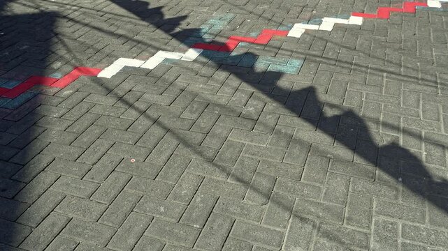Shadows of red and white festive flags cast on textured paving blocks, symbolizing Indonesia independence day celebration and national pride.