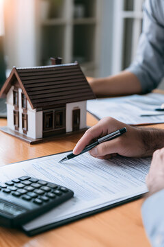 Real Estate Loan Agreement Signing with Calculator and Miniature House Model on Surface