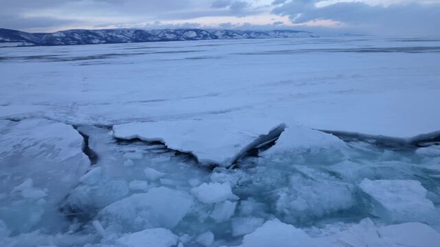View of frozen Lake Baikal with large ice cracks and snow-covered surface in Khuzhir, Irkutsk Oblast, Russia.