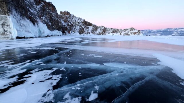 View of frozen Lake Baikal ice with deep cracks and snow patches on the surface in Khuzhir, Irkutsk Oblast, Russia.