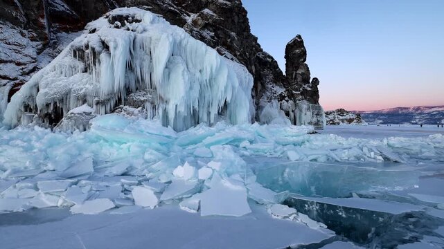 View of frozen Lake Baikal with massive icicles on rocky cliffs and shattered ice blocks on the surface in Khuzhir, Irkutsk Oblast, Russia.