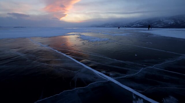 View of the frozen surface of Lake Baikal with deep ice cracks reflecting the sunset light in Khuzhir, Irkutsk Oblast, Russia.