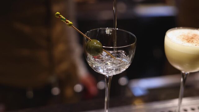 Bartender working, beautiful row line of different coloured liquor alcohol cocktails on a party in a bar, catering banquet on event, barman mixing drinks, selection of beverages in a restaurant club