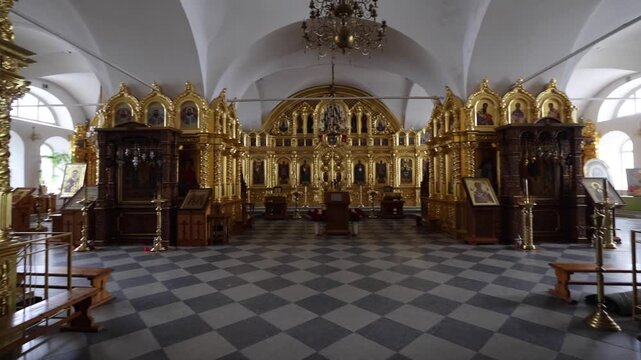 View of the ornate gold-leaf iconostasis and religious icons inside the historic Solovetsky Monastery with a checkered floor in Solovetsky, Arkhangelsk Oblast, Russia.