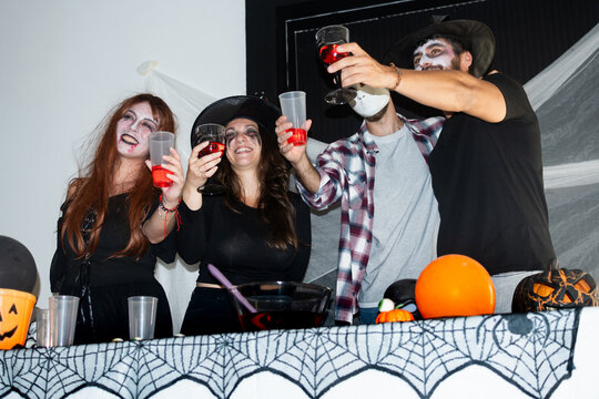 Friends in costumes toasting drinks at Halloween party