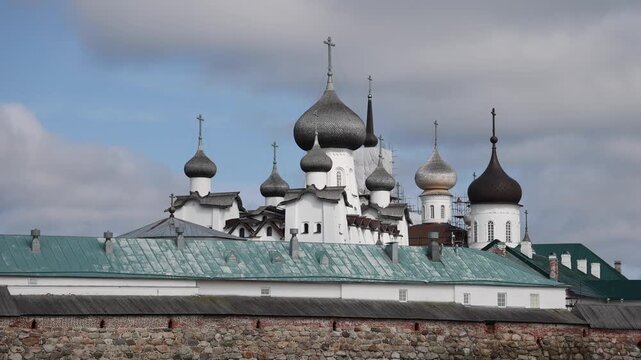 View of Solovetsky Monastery with its distinctive onion domes, historic stone walls, and green roofs under a cloudy sky in Solovetsky, Arkhangelsk Oblast, Russia.