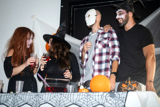 Costumed friends celebrating Halloween with drinks indoors