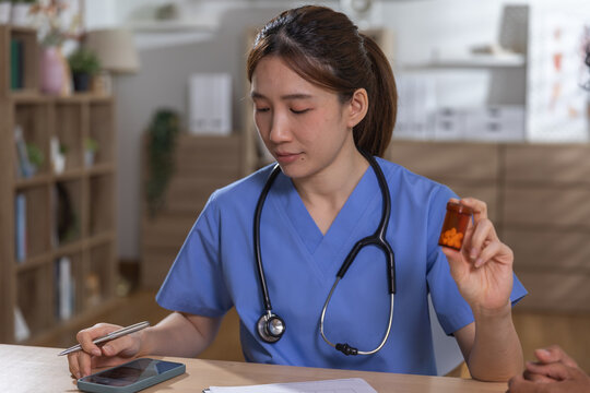 Healthcare medication concept, Nurse holding prescription pill bottle while recording patient information during clinic consultation. nurse, medication, healthcare, prescription, patient.