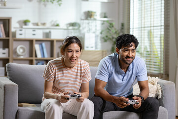 Gaming couple concept. competitive couple plays video games with controllers on sofa at home, showing fun and friendly rivalry. Gaming, couple, competition, entertainment, lifestyle. © eakgrungenerd