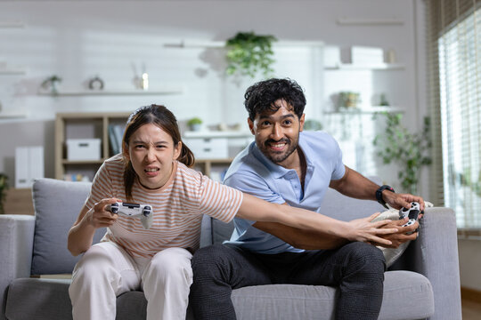 Gaming couple concept. competitive couple plays video games with controllers on sofa at home, showing fun and friendly rivalry. Gaming, couple, competition, entertainment, lifestyle.