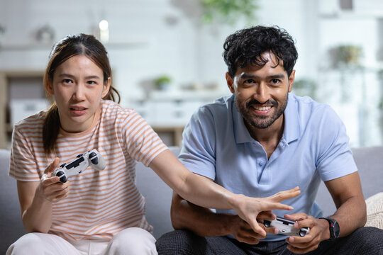 Gaming couple concept. competitive couple plays video games with controllers on sofa at home, showing fun and friendly rivalry. Gaming, couple, competition, entertainment, lifestyle.