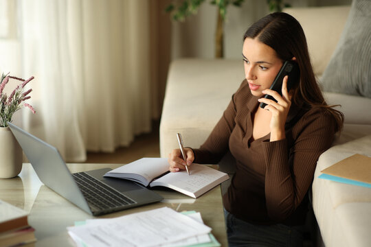 Woman telecommuting talking on phone and writing in agenda