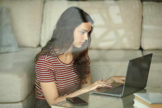 Woman using laptop viewed through a window