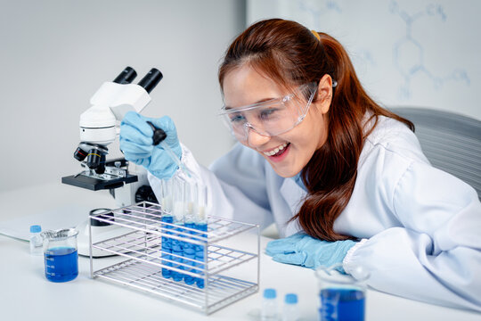 Female scientist conducts chemistry experiment using dropper tes