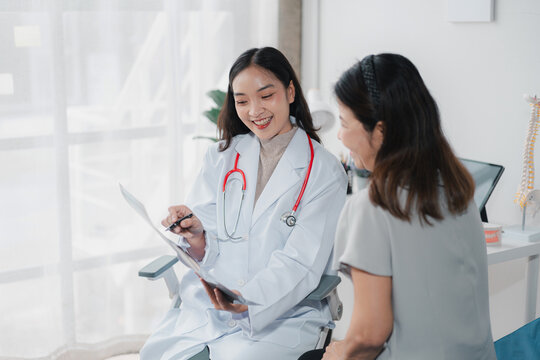 Asian Female Doctor Explaining X-ray to Patient in Clinic Office