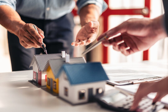 Real estate professional and client reviewing property contract and mortgage documents for home purchase and financing in office