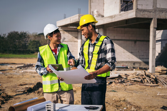 Asian Civil Engineers Inspecting Construction Site Blueprint Pla