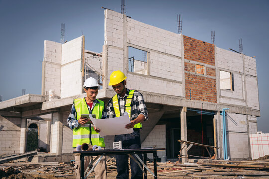 Asian Construction Site Engineers Reviewing Blueprint Plans for