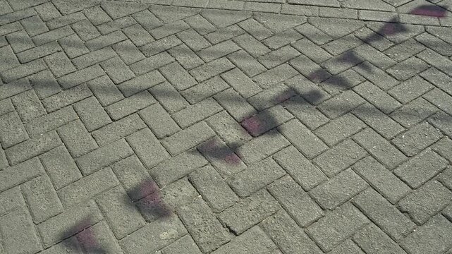 Captivating shadows of festive pennants cast on an outdoor paved block stone ground surface under bright sun, creating a unique abstract texture pattern.