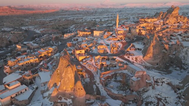 Aerial view of Uchisar castle in Cappadocia Turkey covered with snow during winter sunrise.
