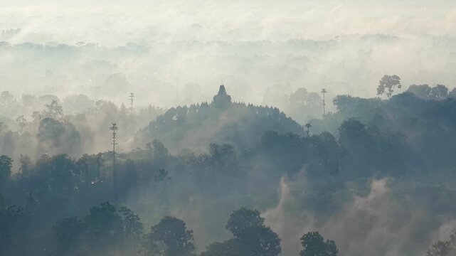 Aerial view of Borobudur temple shrouded in heavy morning mist and fog in Indonesia.