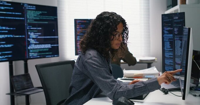 Latin engineer codes a quarantine script while a teammate validates alerts on another terminal, both focused in the server bay.
