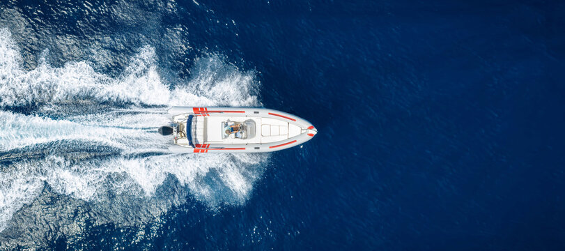 Aerial overhead view of a RIB motorboat cruising with high speed over the ocean with copy space