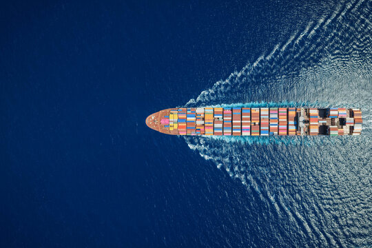High aerial overhead view of a super container cargo ship sailing over open ocean as a banner for shipping and logistics