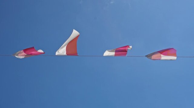 Red and white Indonesian national flags hanging against a clear blue sky, celebrating independence day with national pride.