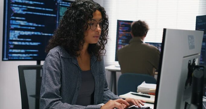 Latin engineer and colleague troubleshoot secure authentication errors beside server racks, exchanging notes as she types.