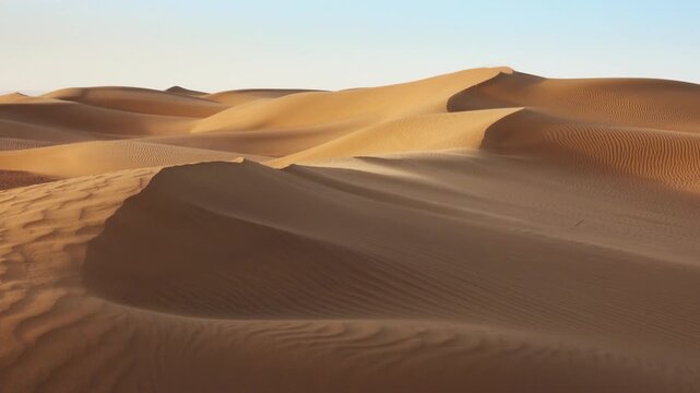 View of the vast golden sand dunes of the Sahara Desert under a clear sky in Morocco.
