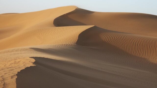 View of Sahara Desert sand dunes with soft ripples and golden light in Morocco.