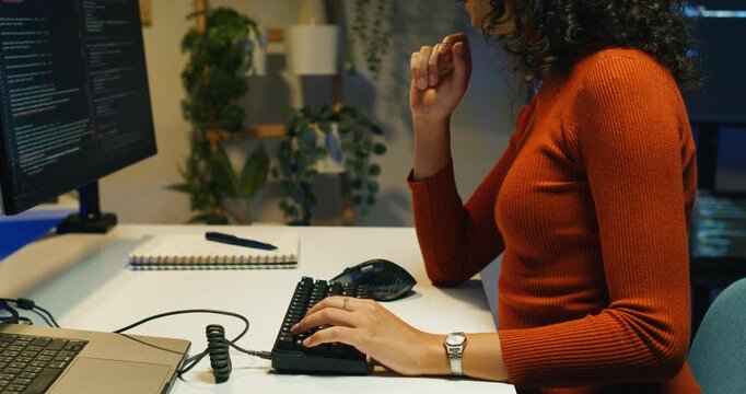  Latin woman engineer reviews cloud deployment logs alone at night, monitoring rollback triggers and scaling rules.

