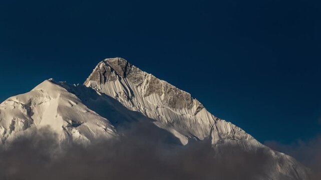 View of the snow-capped Rakaposhi mountain peak rising above the clouds in the Karakoram range near Ali Abad, Gilgit Baltistan, Pakistan.