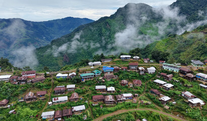 A remote hillside village surrounded by lush green mountains and drifting clouds during the monsoon season in northeastern India. © HAYAVISTA