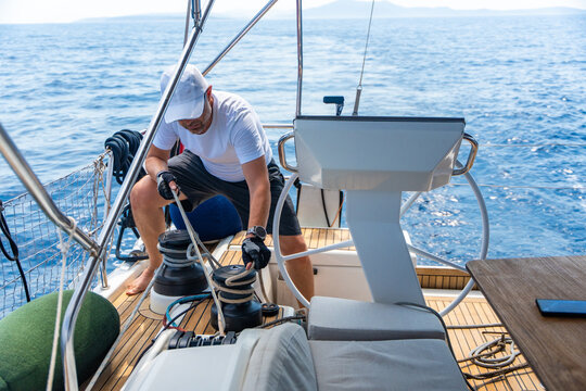 Experienced sailor trimming a sailing line on a modern yacht during an offshore passage. Seamanship, active boat handling, navigation skills and confident cruising under sail.