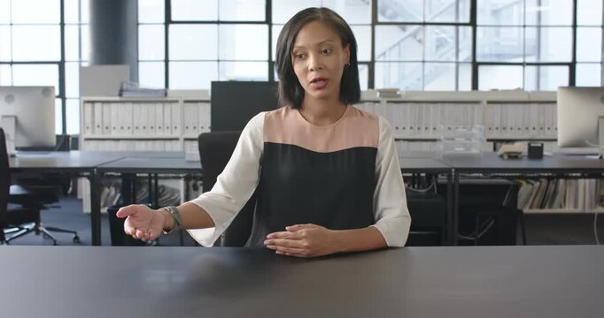 Close up of people talking to the camera, smiling businesswoman sitting at desk, gesturing with hand