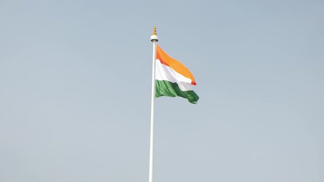 India flag flying high at Connaught Place with pride in blue sky, wavy flag fluttering, Indian Flag on Independence Day and Republic Day of India, tilt up shot, waving Indian flag, Flying ripple flags