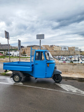 Blue Piaggio Ape 50 three-wheeler / cargo trike parked at the port of Otranto, classic Italian commercial vehicle, Province of Lecce, Apulia, Southern Italy 20.11.2025