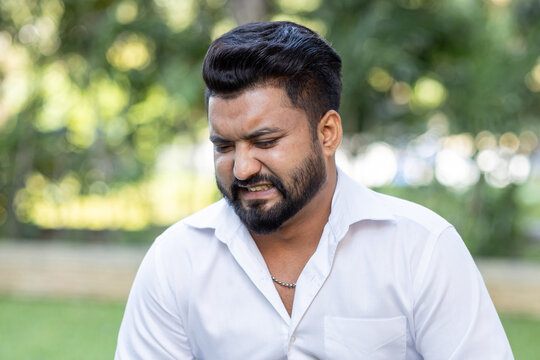 south asian man in his 20s with pained and distressed face, outdoor scene