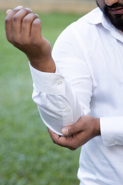 South asian man suffering from elbow joint pain, concept image for tennis elbow or golfer&rsquo;s elbow syndrome, gouty pain, rheumatoid, arthritis, hand holding elbow body parts closeup shot
