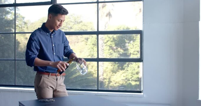 Lifestyle videos indoor of people doing activities at office, man in office pouring beer from bottle
