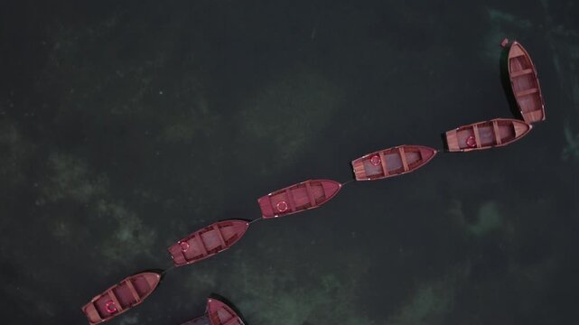 View of wooden boats floating in a line on the clear water of Pragser Wildsee in Prags, Trentino-Alto Adige, Italy.