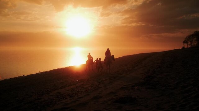 View of people riding horses along the beach at sunset near ARYA Sumba in Kodi, East Nusa Tenggara, Indonesia.